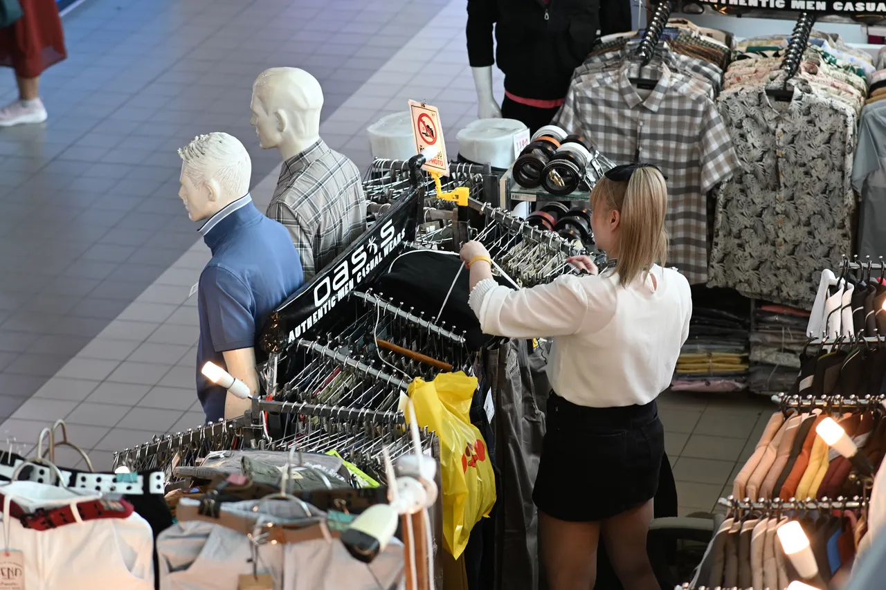 Symbolbild: Person stöbert an einer gut gefüllten Kleiderstange